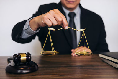 Midsection of lawyer holding golden weight scale in courtroom