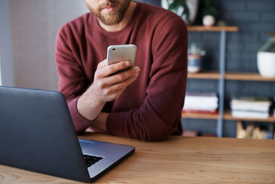 Midsection of woman using mobile phone at table