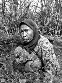 Portrait of old woman sitting on field