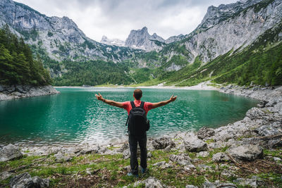 Rear view of man standing in lake against mountains