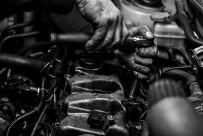 Cropped hands of manual worker repairing engine