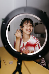 Portrait of a smiling young woman holding camera