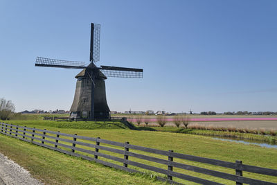 Traditional windmill on field against clear sky