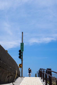 Woman standing by building against blue sky