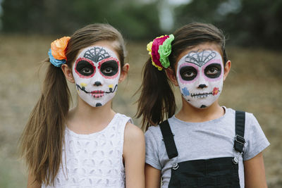 Portrait of sisters with face paint during halloween