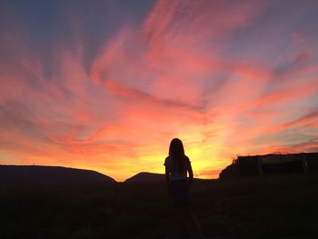 Silhouette woman standing against orange sky