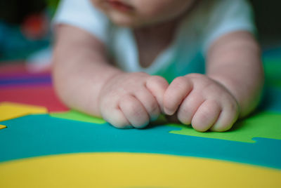 Close-up of toddler lying on multi colored sheet