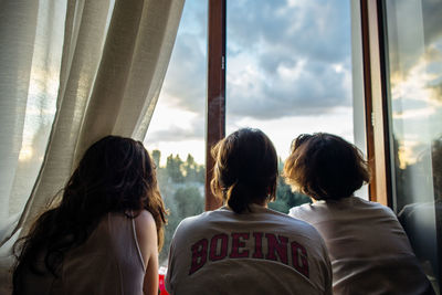 Rear view of people looking through window