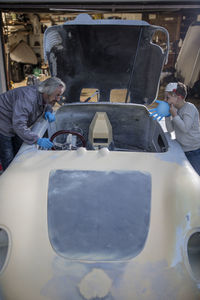 Senior man and boy working on old car together