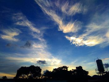 Low angle view of silhouette trees against dramatic sky