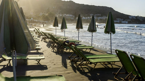 Parasols and lounge chairs at beach against clear blue sky