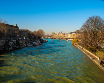 Canal amidst buildings against clear blue sky