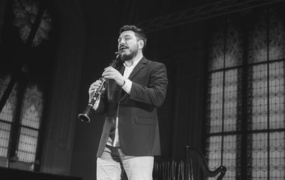 Man playing clarinet while standing at studio