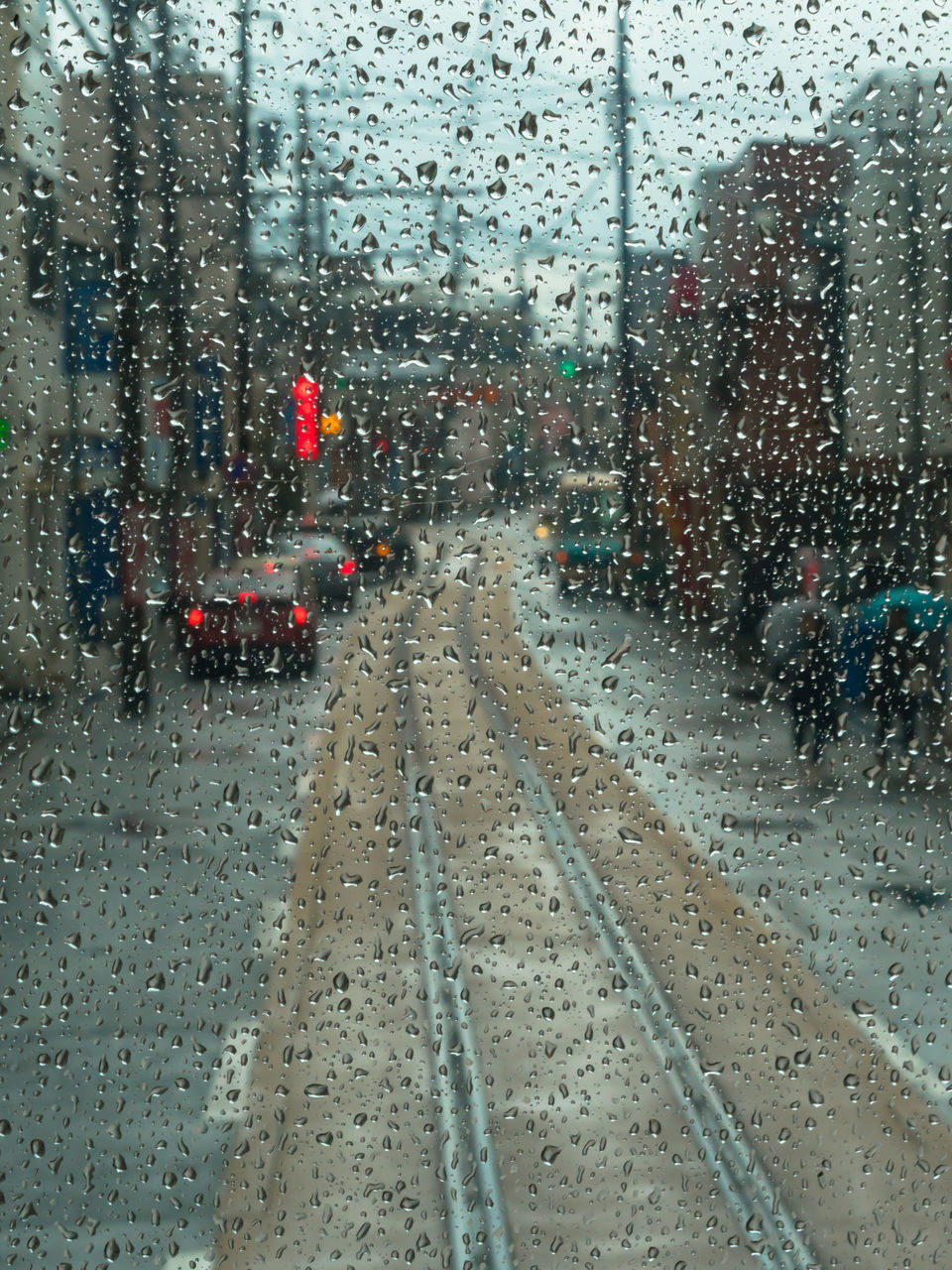 CARS ON ROAD SEEN THROUGH WET WINDOW