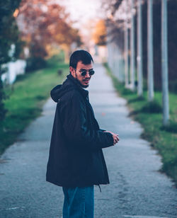 Portrait of smiling young woman standing on footpath