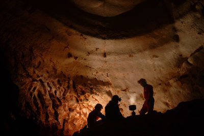 Silhouette friends relaxing in cave