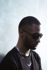 Portrait of young man wearing sunglasses against wall