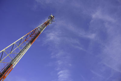 Low angle view of crane at construction site against blue sky