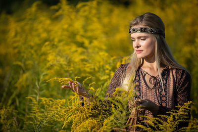 Portrait of young woman standing amidst plants