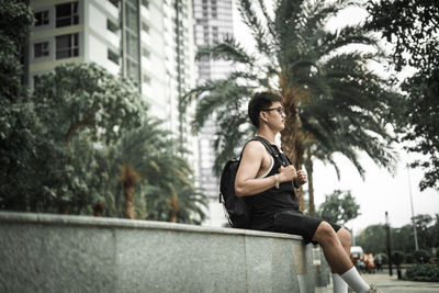 Young woman sitting against trees