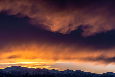 Scenic view of mountains against dramatic sky during sunset