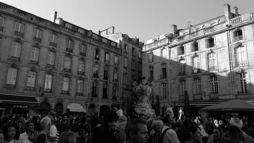 Crowd standing in front of city against sky