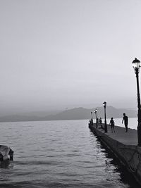 People on sea against clear sky