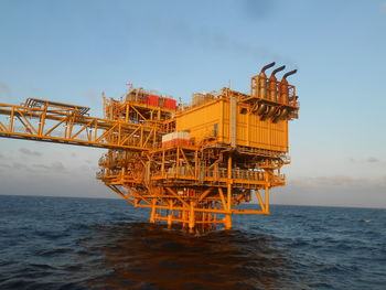 Traditional windmill by sea against sky