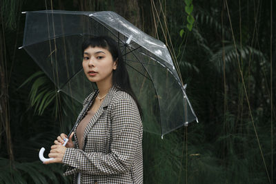 Portrait of beautiful young woman standing against plants