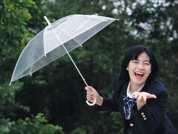 Portrait of happy woman holding umbrella during rainy season