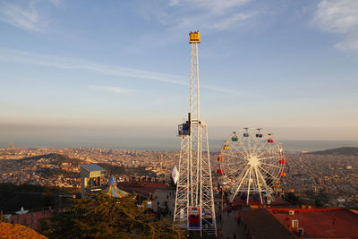 High angle view of ferris wheel by buildings against sky