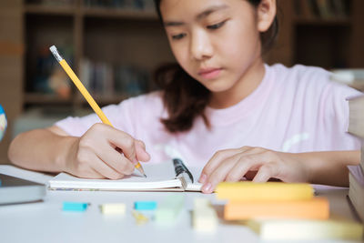 Girl writing while sitting in library