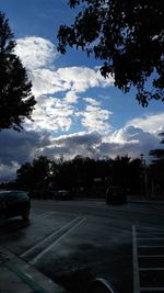 Cars on road against cloudy sky