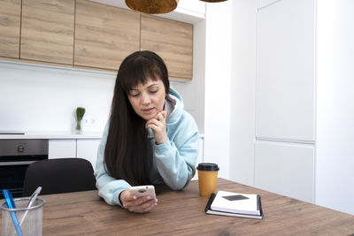 Young woman using mobile phone at home