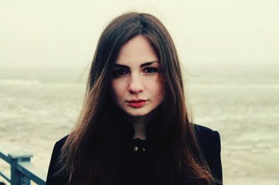 Close-up portrait of young woman against sea