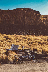 Abandoned car on land against sky