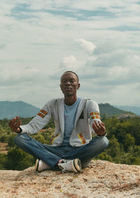Portrait of young man sitting against sky