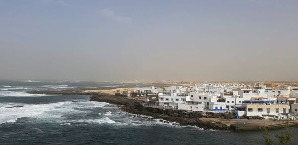 Sea by buildings against sky in city