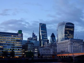 Modern buildings in city against sky at dusk