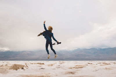 Full length of man jumping on mountain against sky