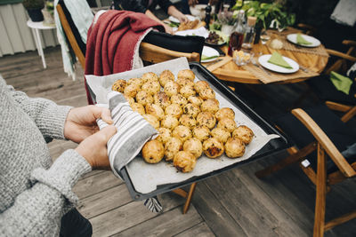 Low section of senior man holding baking sheet with baked potatoes at back yard during dinner party
