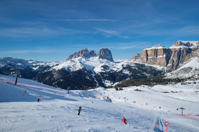 People skiing on snowcapped mountain against sky