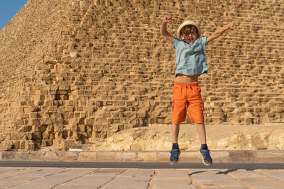 Happy boy jumping in front of the cheops pyramid on the giza plateau