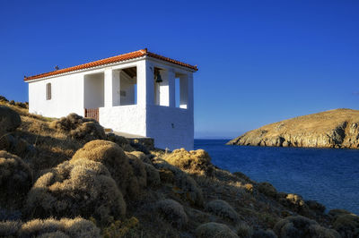 Building by sea against clear blue sky