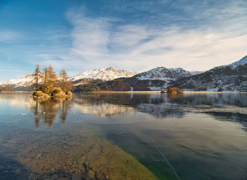 Scenic view of frozen lake by snowcapped mountains against sky