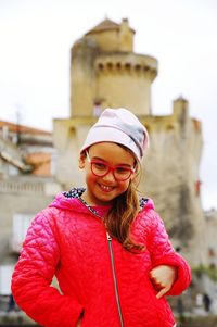 Smiling cute girl standing against building