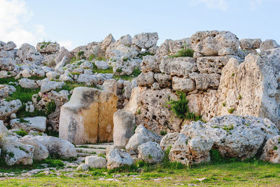 Stone wall by rocks against sky