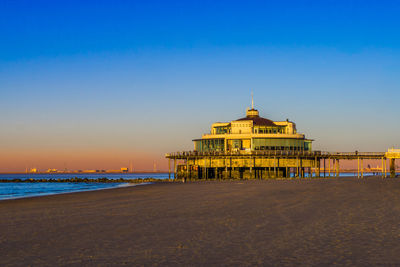 Building on beach against clear sky during sunset