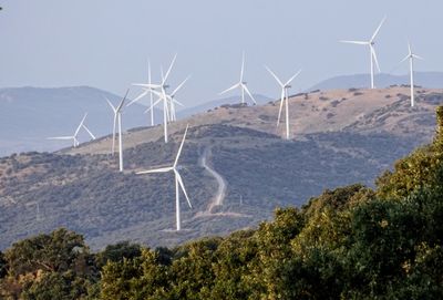 Wind turbines on landscape against sky