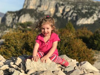 Cute girl sitting on rocks pile